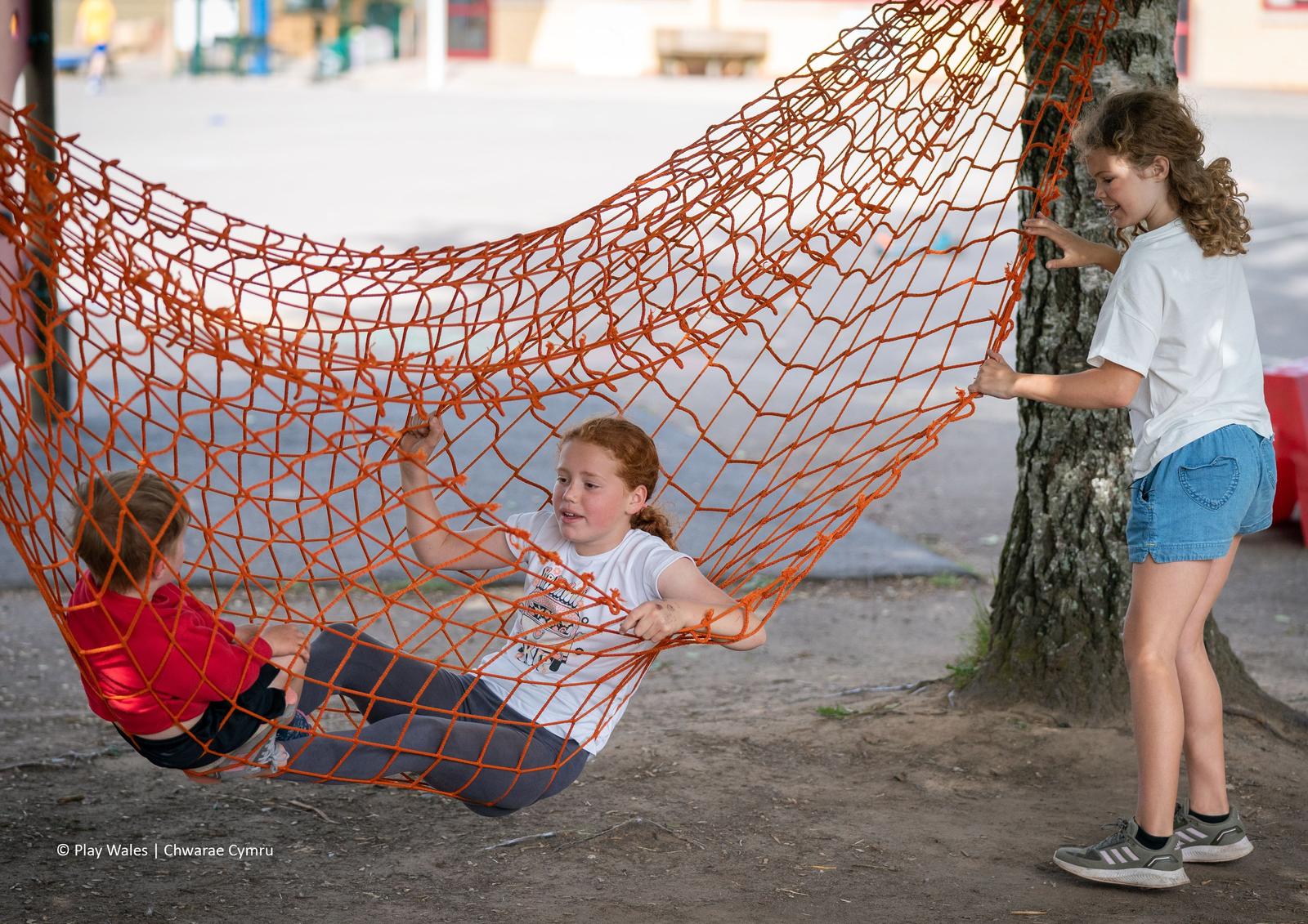 Tri phlentyn yn chwarae gyda rhwyd cargo